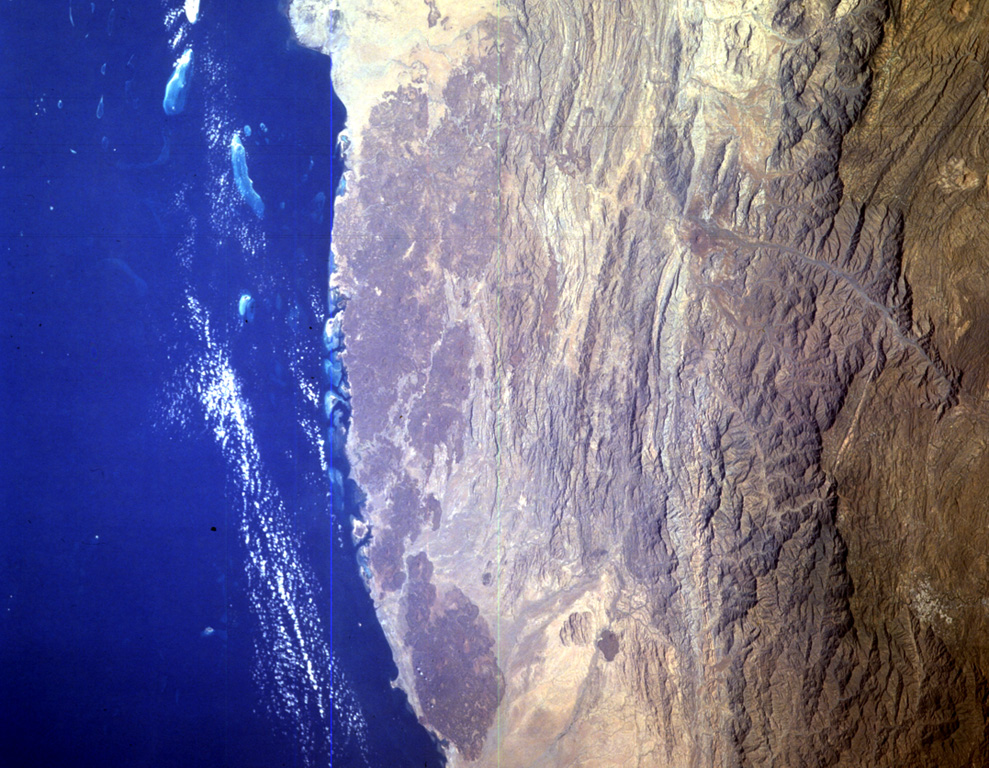 The Harrat al Birk volcanic field forms the dark-colored area between the Red Sea coast and the center of this NASA Space Shuttle image (N to the upper right). This 1,800 km2 Miocene and Quaternary volcanic field separates the Tihamat ash Sham and Tihamat 'Asir coastal plains. Scoria cones occur throughout the field and a few outlying cones lie E of the main lava field. NASA Space Shuttle image STS055-151-184, 1993 (http://eol.jsc.nasa.gov/).