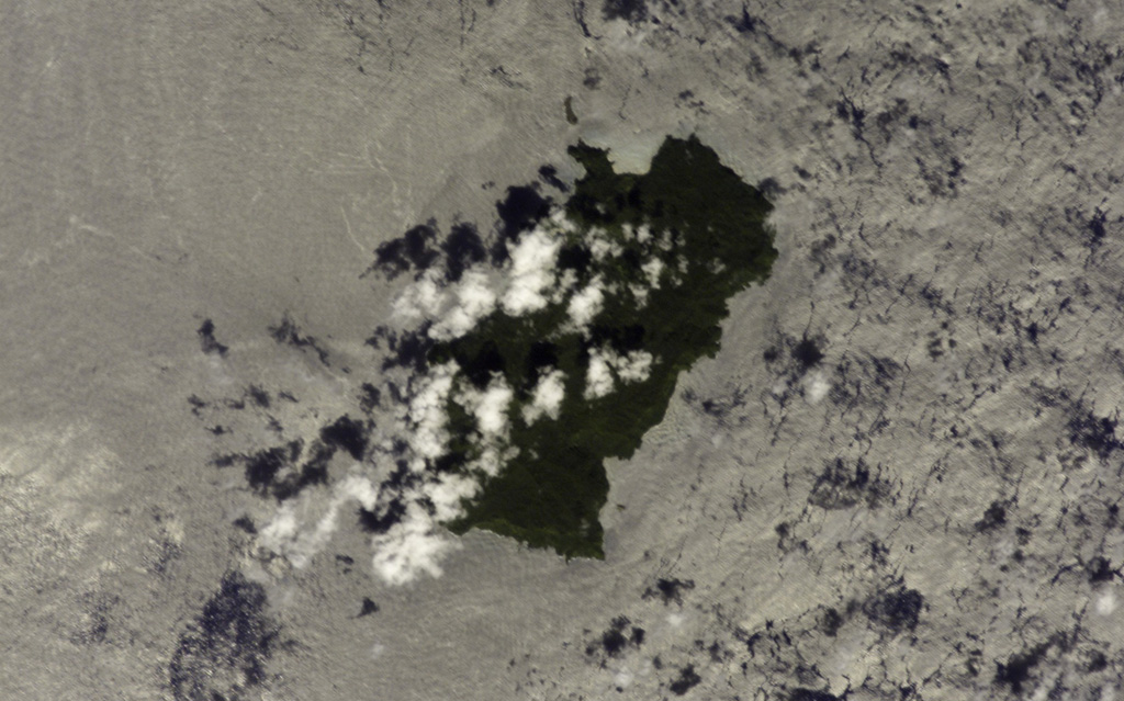 Clouds partially obscure the 22 km2 Isla del Coco (Cocos Island) in this NASA International Space Station image.  Chathan Bay (top) lies off the NE tip of the island, which sits astride the Cocos Ridge about 650 km SW of the Costa Rican port of Puntarenas.  The rain-drenched island is renowned as the site of treasures buried by pirates and ship captains.   Construction of a Pliocene-Pleistocene shield volcano was followed by caldera formation and the emplacement of a trachytic lava dome. NASA International Space Station image ISS004-E-7510, 2002 (http://eol.jsc.nasa.gov/).