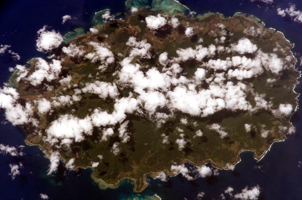 Clouds drape oval-shaped, 17-km-wide Aneityum Island in this NASA International Space Station image with north to the top. Aneityum, also known as Anatom, consists of two coalescing, dominantly basaltic Pleistocene volcanoes. Both the NW side of Inrerow Atamwan volcano (left) and the SE side of Nanawarez volcano (right) are truncated by large erosional cirques. Volcanic activity ceased during the late-Pleistocene to Holocene. Fringing reefs are visible on the northern side of the island. NASA International Space Station image ISS006-E-5732, 2002 (http://eol.jsc.nasa.gov/).