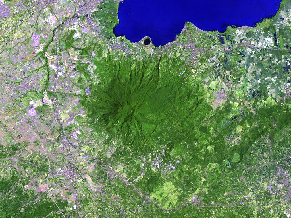 The forested Maquiling volcano (center) rises south of Laguna de Bay (top) and is the highest point of the San Pablo volcanic field. It has a deep crater whose floor is 480 m below its N rim and several cones, maars, and numerous thermal areas at its northern base, and other maars and scoria cones of the San Pablo volcanic field lie to the E. The prominent dark-colored maar along the shore of Laguna de Bay north of Maquiling is Alligator Lake. NASA Landsat image, 2002 (courtesy of Hawaii Synergy Project, Univ. of Hawaii Institute of Geophysics & Planetology).