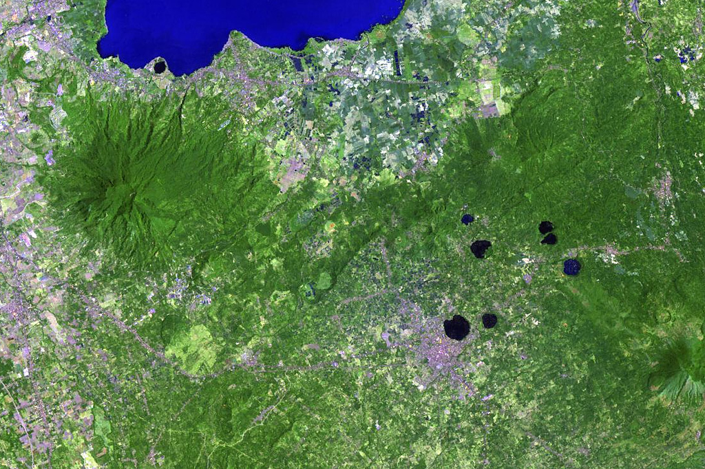Lake-filled maars are common features of the San Pablo Volcanic Field at the southern end of the large Laguna de Bay (top). The monogenetic volcanic field contains a group of 42 scoria cones and 36 maars, the youngest of which contain deep lakes. The largest maar in this Landsat image is 1.2-km-wide Sampaloc Lake, immediately N of the city of San Pablo. Local legends suggest that this maar formed about 500-700 years ago. The forested volcano to the left is Maquiling. NASA Landsat image, 2002 (courtesy of Hawaii Synergy Project, Univ. of Hawaii Institute of Geophysics & Planetology).