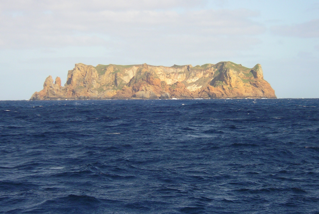 Flat-topped Curtis Island, seen here from the N, is, along with nearby Cheeseman Island, the uplifted portion of a submarine volcano astride the Kermadec Ridge. The small Pleistocene island contains abundant andesitic pyroclastic flow deposits. Reports of possible historical eruptions probably represent increased thermal activity from a shallow crater near sea level. Geologic studies have documented uplift of 18 m at Curtis during the past 200 years. Photo by Owen Calder, 2004