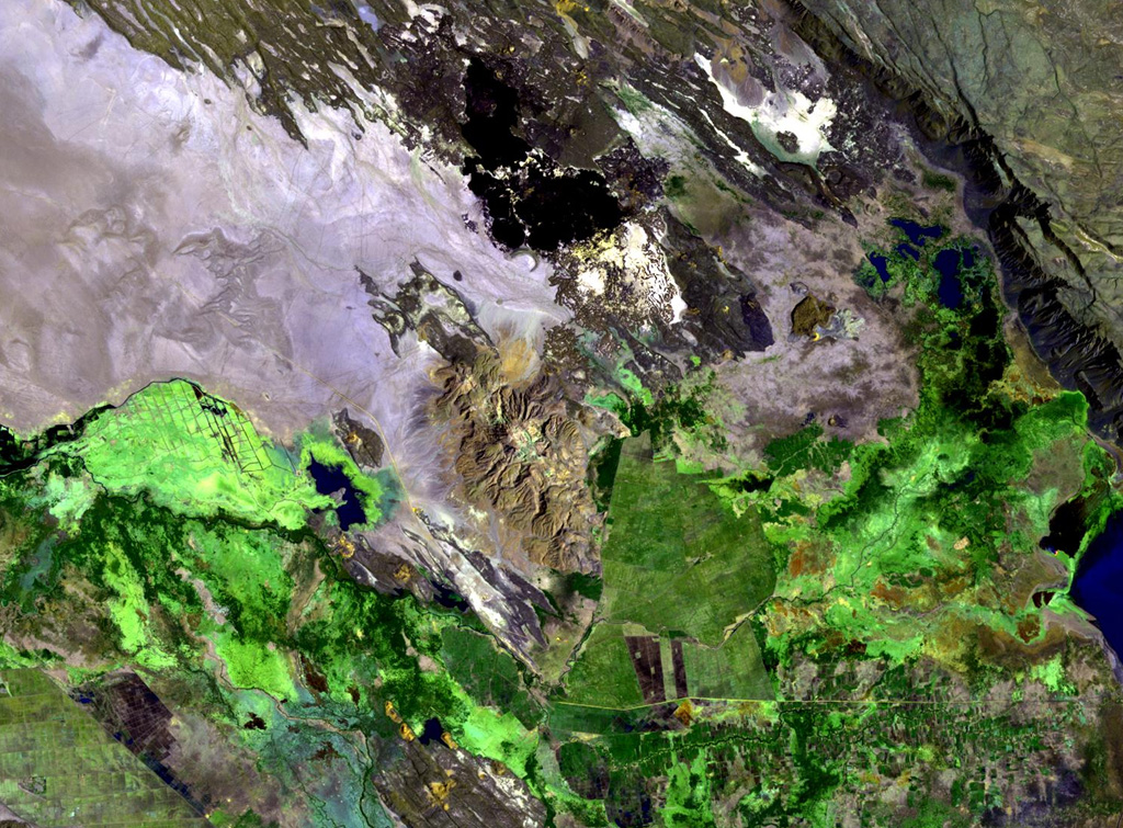 The brownish-colored Borawli complex (center) consists of a group of rhyolitic lava domes on the floor of the southern Kali Plain. Dark-colored, youthful looking basaltic lava flows (top) were erupted from fissures north of the dome complex, one of several volcanic features in Ethiopia named Borawli. The edge of Uddummi lake is visible at the lower right. NASA Landsat image, 1999 (courtesy of Hawaii Synergy Project, Univ. of Hawaii Institute of Geophysics & Planetology).