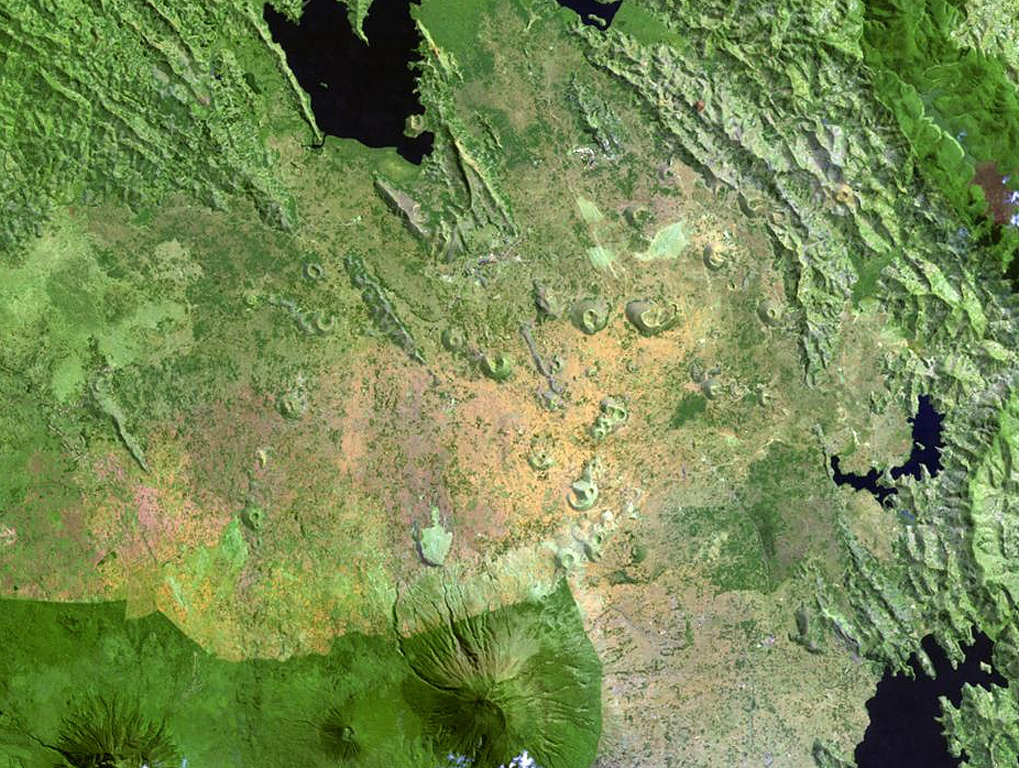 Scoria cones of the Bufumbira volcanic field in SW Uganda (center) lie N of the large stratovolcanoes of the NE part of the Virunga Mountains. The roughly 40 scoria cones occur in clusters and were erupted along lineaments and are typically breached on one side by lava flows. The Bufumbira rocks are noted for their unusual ultrapotassic chemistry. Muhavura (center) and Sabinyo (left) stratovolcanoes are visible at the bottom of this Landsat image. NASA Landsat image, 1999 (courtesy of Hawaii Synergy Project, Univ. of Hawaii Institute of Geophysics & Planetology).