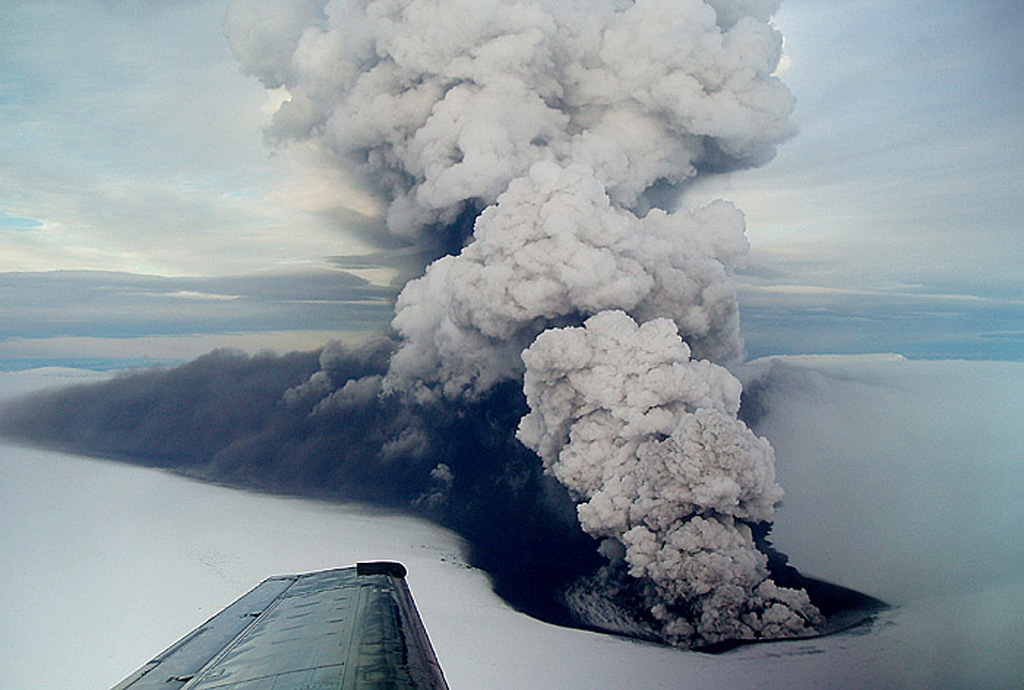 An ash plume rises from a new crater near the southern margin of Grímsvötn caldera in November 2004. Grímsvötn lies largely beneath the vast Vatnajökull icecap and the eruption melted its way through ice about 200 m thick. The plume extends towards the north due to the wind direction, coating the surface of the glacier in dark ash. Photo by Freysteinn Sigmundsson, 2004 (Nordic Volcanological Center).