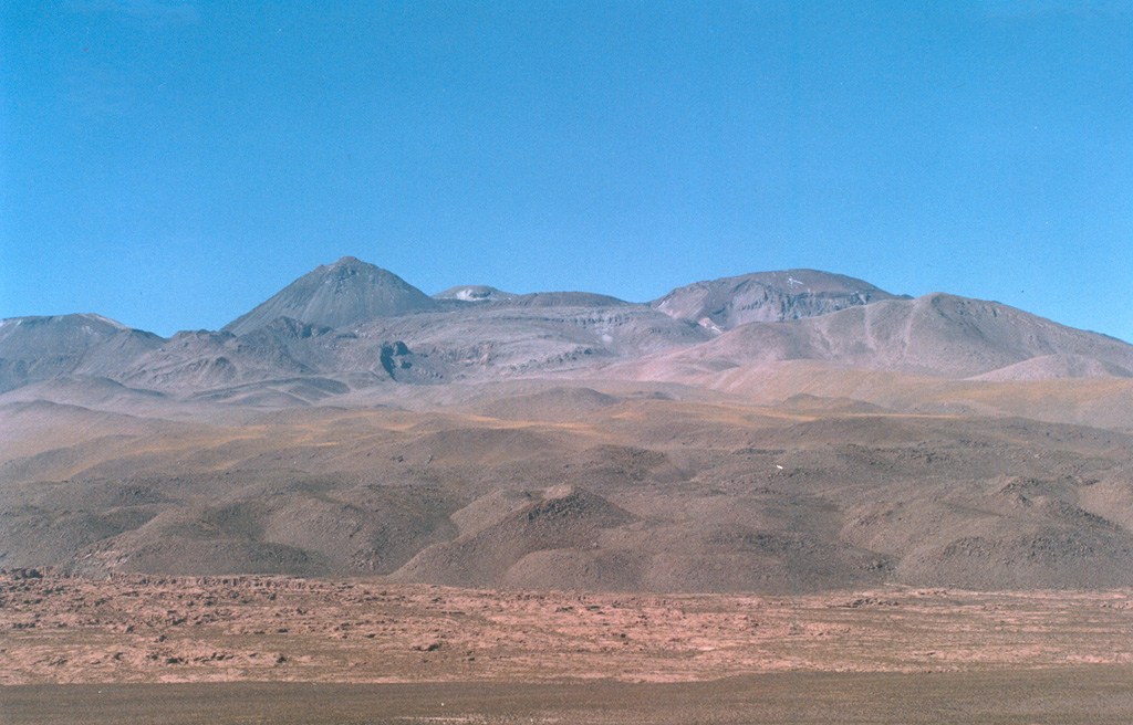 The western side of the Sairecábur volcanic complex is seen with thick, blocky lava flows in the foreground.  This chain of andesitic-dacitic volcanoes along the Chile-Bolivia border contains at least 10 postglacial centers and stretches from Escalante volcano on the north to Sairecábur volcano on the south.  The highest peak, Sairecábur, is located on the northern margin of a 4.5-km-wide caldera.  An active sulfur mine is located north of the volcano.  Escalante has a crater lake at its summit and youthful lava flows on its flanks. Photo by Raphaél Paris, 2004 (CNRS, Clermont-Ferrand).