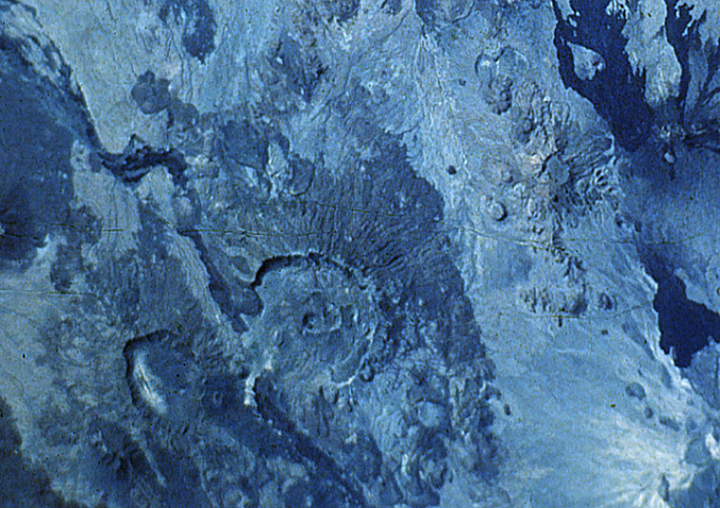 The large caldera below and to the left of the center of this Space Shuttle photo of the Danakil Alps of Ethiopia is Nabro. This volcano is the highest in the Danakil depression and is truncated by nested calderas 10 and 5 km in diameter. The larger caldera is breached to the SW. The 8-km-wide Mallahle caldera is at the lower left, and the dark-colored lava flows at the right are from Dubbi volcano. NASA Space Shuttle image S-61A-36, 1985 (http://eol.jsc.nasa.gov/).
