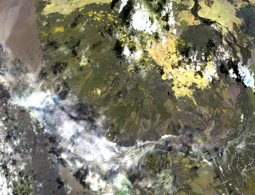 Asavyo volcano, near the center of this NASA Landsat image, is the SW-most of three large silicic stratovolcanoes of uncertain age constructed along a NE-SW-trending line in the Danakil horst. Basaltic lava flows blanket the flanks of Asavyo, which merge into the Mogorros plains to the south. The caldera at the bottom right-center is Oyma volcano, Mallahle volcano lies beneath the clouds at the top center, and Sorkale volcano occupies the circular dark-colored area at the upper right. NASA Landsat image, 1999 (courtesy of Hawaii Synergy Project, Univ. of Hawaii Institute of Geophysics & Planetology).