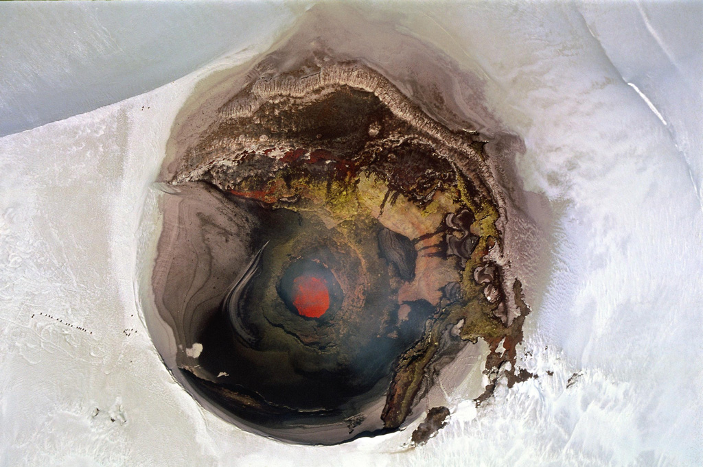 A near-vertical aerial view into the ~250-m-wide summit crater of Villarrica volcano on November 19, 2004 shows an incandescent lava lake in the steep-walled inner crater.  The chain of dots left (north) of the crater are climbers near the crater rim.  Night-time glow was periodically visible from the town of Pucón on the north flank of volcano beginning in August 2004 and intensified in November and December.  Small strombolian explosions in December ejected spatter and bombs onto the crater rim.  Photo by Jean-Claude Tanguy, 2004 (Institute de Physique du Globe de Paris).