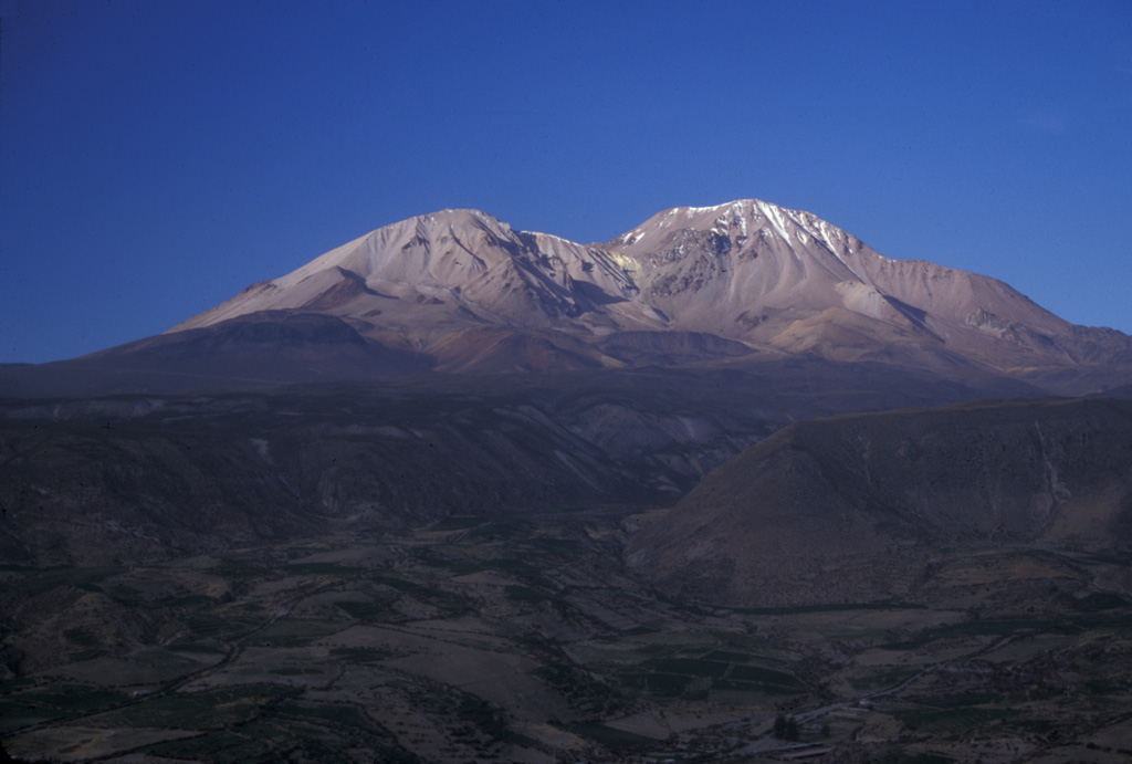 The Taapaca volcanic complex rises to the NE above the town of Putre, just out of view to the left.  The elongated volcanic massif consists of an initial andesitic stratovolcano and a long-term dacitic lava-dome complex.  The 5860-m-high dome complex on the right horizon is part of the Holocene Putre unit, formed during the latest eruptive stage.  The left-hand dome is part of the late-Pleistocene Socapave unit.  A pyroclastic apron from Taapaca, including a late-Pleistocene debris-avalanche deposit, forms the foreground. Photo by Lee Siebert, 2004 (Smithsonian Institution).
