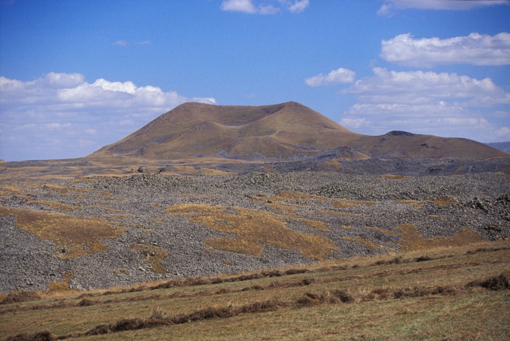 A lava flow extends across the foreground from a cone within the Porak volcanic field, located along the Vardeniss volcanic ridge about 20 km SE of Lake Sevan. The volcanic field straddles the Armenia/Azerbaijan border, and lava flows extend into both countries. This lava flow is the youngest of the volcanic field. Another flow from the same cone (located in Armenia) flowed into Lake Alagyol in Azerbaijan. Archaeological and historical evidence indicates several eruptions occurred during the Holocene. Photo by Jim Luhr, 2004 (Smithsonian Institution).