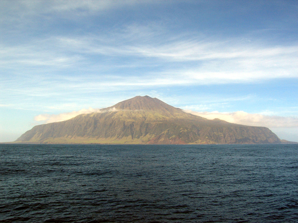The southwest side of Tristan da Cunha volcano rises above the southern Atlantic ocean. The summit cone Queen Mary’s Peak towers above high cliffs along most of the 12-km-wide island. Lava flows dominate both the low-angle base and the steep upper flanks, although pyroclastic cones ringing the central cone are scattered around the lower flanks. An eruption in 1961 occurred from a vent on the northern coast, just east of the island's only settlement, Edinburgh of the Seven Seas, forcing its evacuation.  Photo by Vicky Hards, 2004 (British Geological Survey, copyrighted NERC).