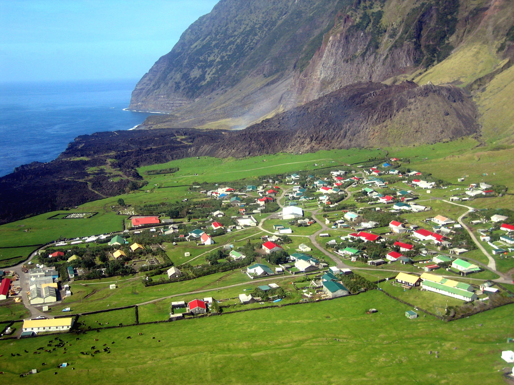 A lava flow on Tristan da Cunha extends approximately 700 m to the sea from a small lava dome formed during the eruption of 1961-1962. The flow is seen here from the SW with the island's only habited area, the village of Edinburgh of the Seven Seas, in the foreground. The eruption began on 10 October 1961 and prompted the evacuation of the island's entire population to England. The eruption ended on 15 March 1962, and resettlement began in September of that year. Photo by Vicky Hards, 2004 (British Geological Survey, copyrighted NERC).