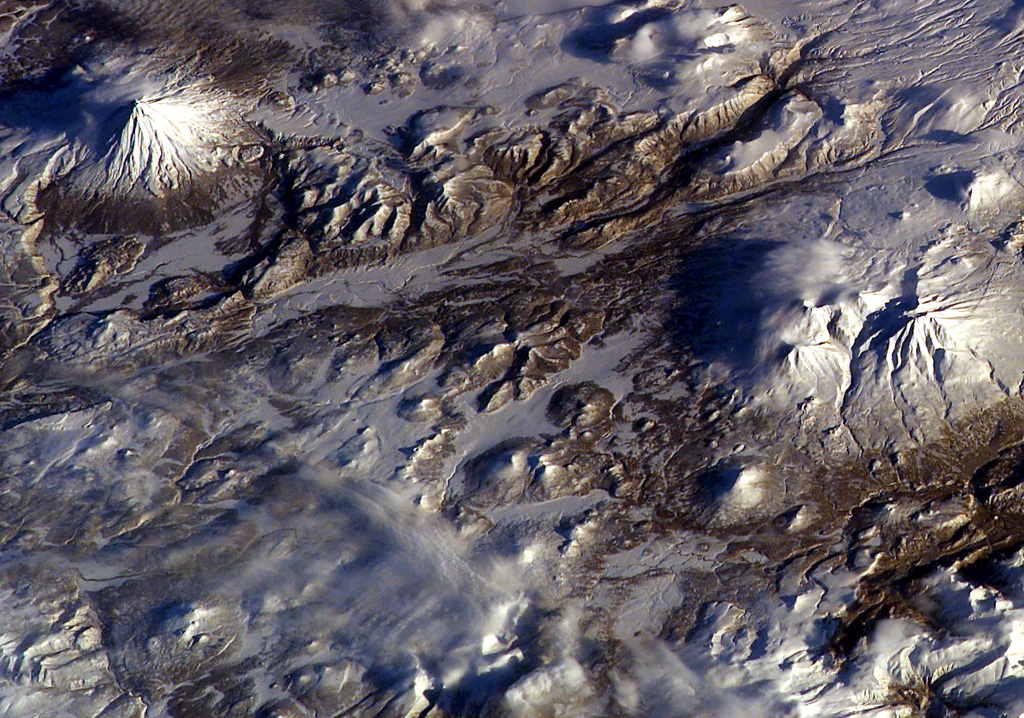 A large group of small cones is in the bottom-center of this NASA International Space Station image (with N to the top). Otdelniy, Tundroviy and other adjacent unnamed features are surrounded by a large group of late-Pleistocene to Holocene cones SE of Opala (the conical volcano to the upper left) and SW of Asacha volcano to the right. NASA International Space Station image ISS006-E-36667, 2003 (http://eol.jsc.nasa.gov/).