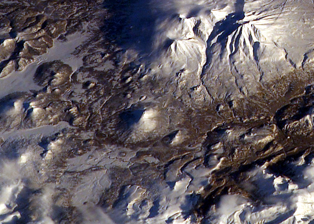 The small snow-covered cone in the center of this NASA International Space Station image (with N to the top) is Golaya. This small, Pleistocene-to-Holocene cone lies SW of Asacha (top-right). The summit is elongated in a N-S direction and overlooks small cones to the W that formed during basaltic volcanism. NASA International Space Station image ISS006-E-36667, 2003 (http://eol.jsc.nasa.gov/).