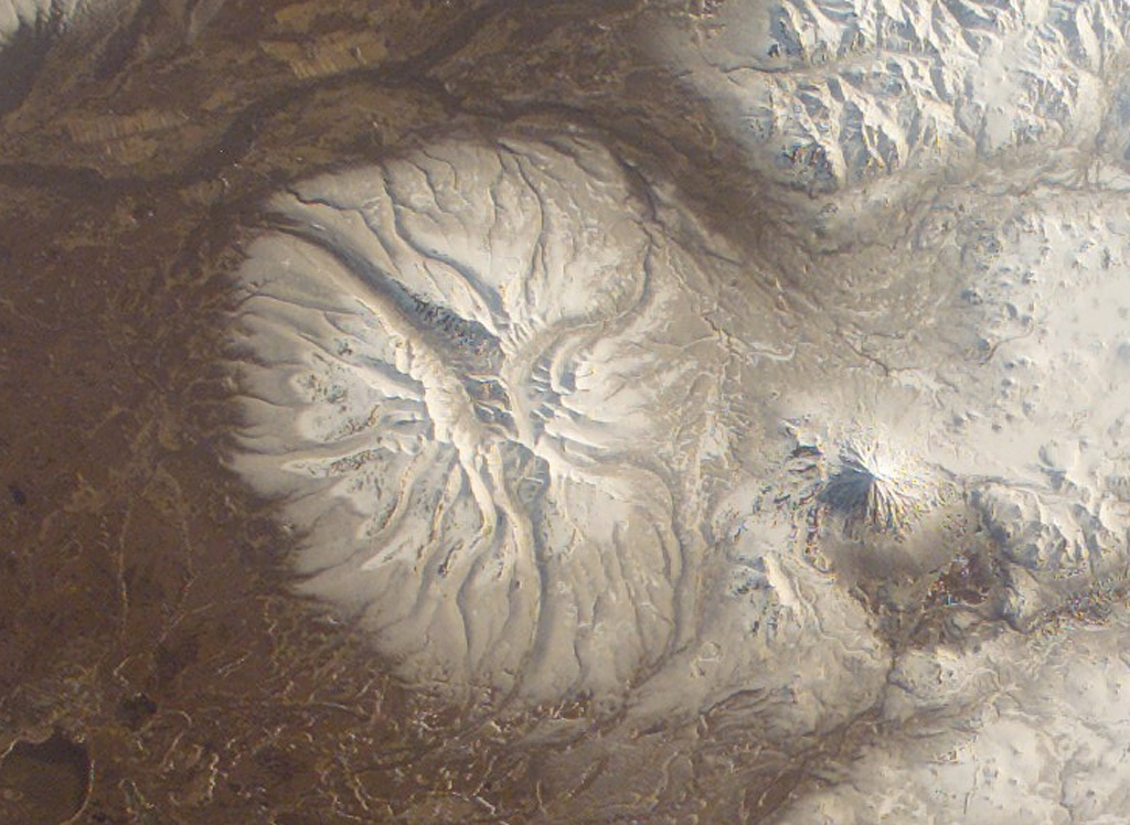 The early Pleistocene Bolshaya Ipelka volcano has been extensively eroded by glaciers and has a single unnamed Holocene scoria cone on the southern flank. The conical stratovolcano to the E (right) is Opala, which was constructed along the northern rim of a large 12 x 14 km wide caldera. NASA International Space Station image ISS004-E-11691, 2002 (http://eol.jsc.nasa.gov/).