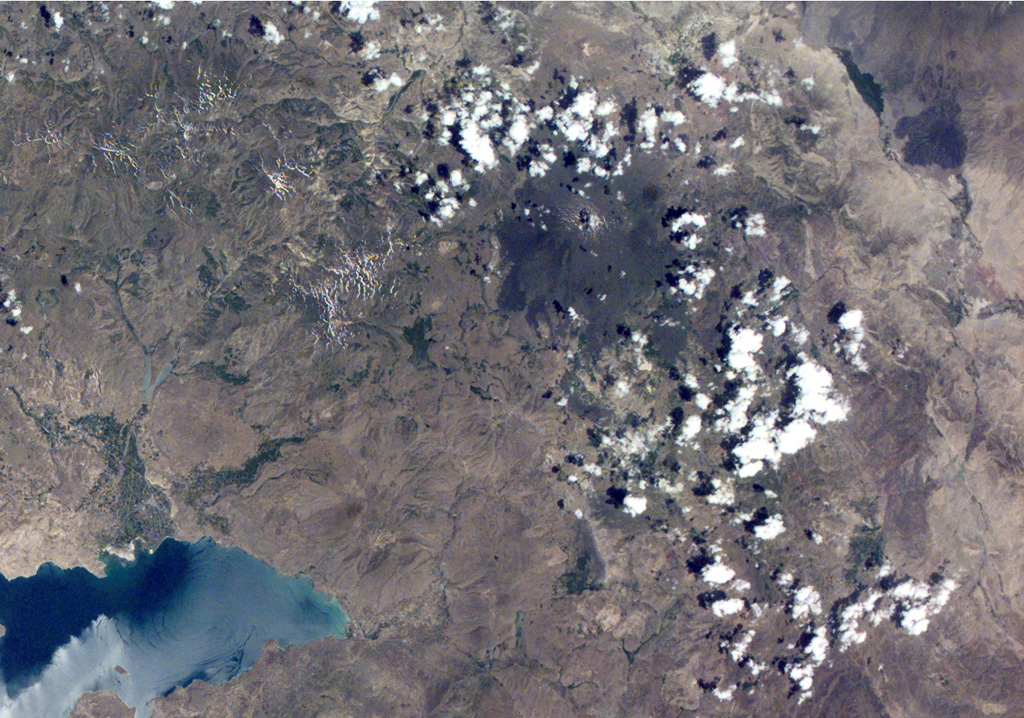 The dark-colored circular area above and to the right of the center of this NASA International Space Station image (with north to the top) is Tendürek Dagi. This shield volcano rises 1,800 m above the plain of Dogubayazit, near the Iranian border, NE of Lake Van (whose NE tip is at the lower left) and S of Mount Ararat (out of view to the upper right). An eruption took place from a vent on the SE flank of Tendürek Dagi about 2,500 years ago, and another eruption occurred in 1855. NASA International Space Station image ISS002-E-7778, 2001 (http://eol.jsc.nasa.gov/).
