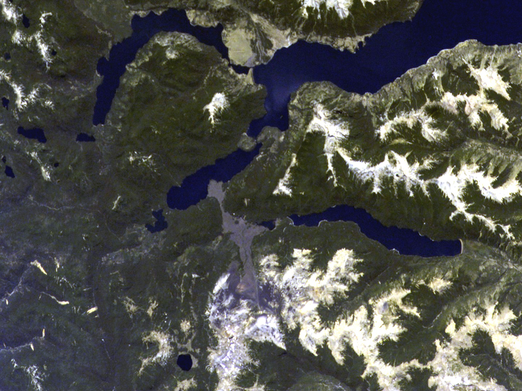 The linear grayish lava flow extending into two lakes at the center originated from the Achín-Niellu cinder cone in the snow-covered area at the bottom-center of this NASA Space Station image with north to the upper left.  The distal end of 7.5-km-long flow forms a large delta into Lago Epulafquen.  A cinder cone separates this lake (known in the Machupe language as "Two Lakes") from the large lake at the upper right, Lago Huechulafquen.  The lake at the right-center is Lago Curruhué.  NASA International Space Station image ISS004-E-7197, 2002 (http://eol.jsc.nasa.gov/).