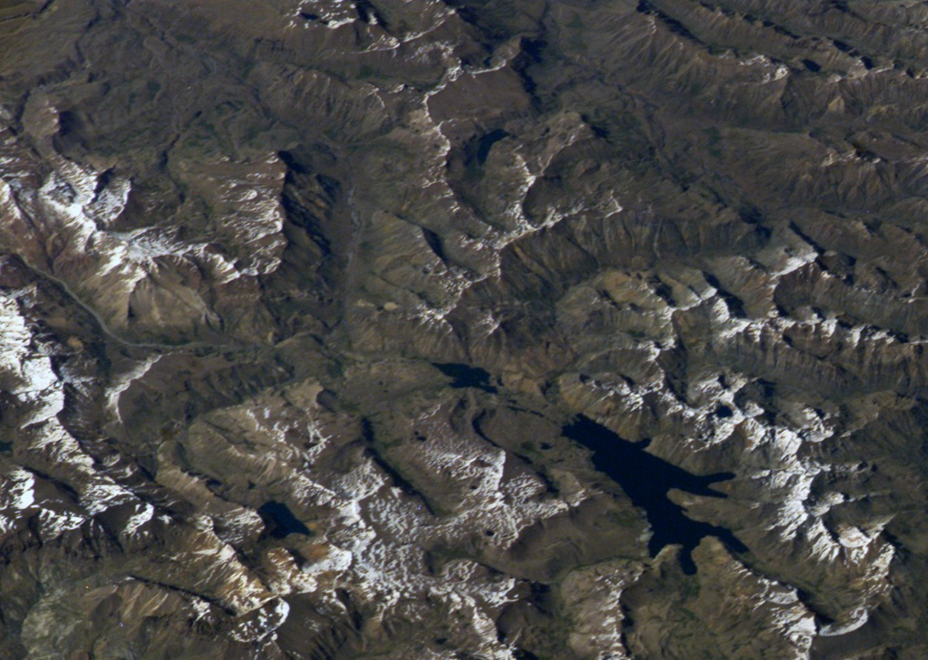 The snow-covered area at the upper left in this NASA International Space Station image (with north to the lower right) is the Volcán Domuyo volcanic complex.  This 4709-m-high Argentinian volcano contains at least 14 dacitic lava domes and other eruptive centers within a 16-km-wide caldera, and at least another 5 lie outside the caldera.  Elongated Laguna Valvarco at the lower right lies along the western margin of the Pleistocene Valvarco caldera. NASA International Space Station image ISS008-E-7432, 2003 (http://eol.jsc.nasa.gov/).