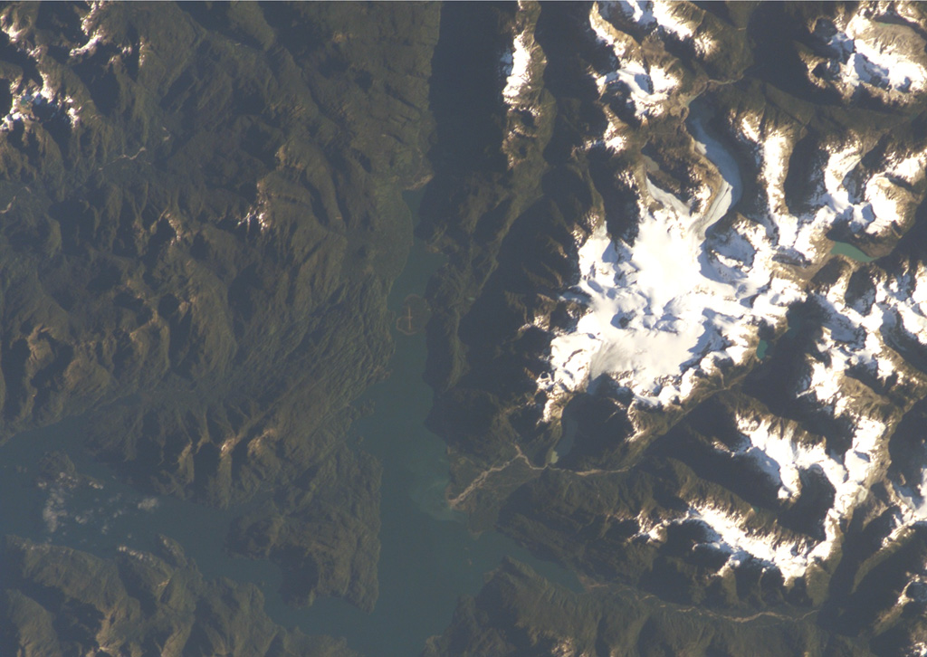 A chain of cinder cones was erupted along NE-SW-trending fissures at the head of Puyuhuapi fjord (top-center) in this NASA International Space Station image (with north to the upper left).  The Volcanes de Puyuhuapi consists of a larger group of four cones on the western side of Puyuhuapi fjord and a chain of smaller cones north of the head of the fjord.  The two fractures and the fjord are related to the regional Liquiñe-Ofqui fault zone.  The town of Puyuhuapi lies on the western side of the fjord, about halfway down its visible length in this image.  NASA International Space Station image ISS004-E-7079, 2002 (http://eol.jsc.nasa.gov/).