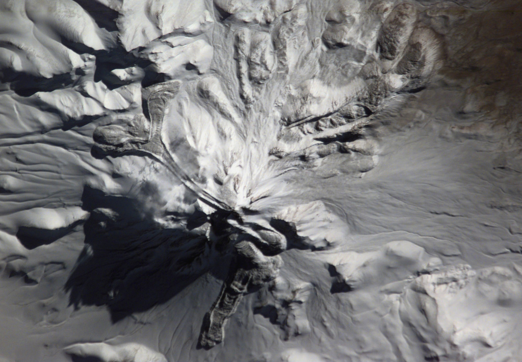 The snow-mantled surface of Llullaillaco volcano is seen in this NASA International Space Station image (with north to the upper left).  The two youthful looking lava flows with prominent flow levees descending the northern and western flanks of the volcano appeared to be of Holocene, but Ar/Ar dating showed them to be of late-Pleistocene age. Llullaillaco is the world's highest historically active volcano. NASA International Space Station image ISS006-E-13814, 2003 (http://eol.jsc.nasa.gov/).