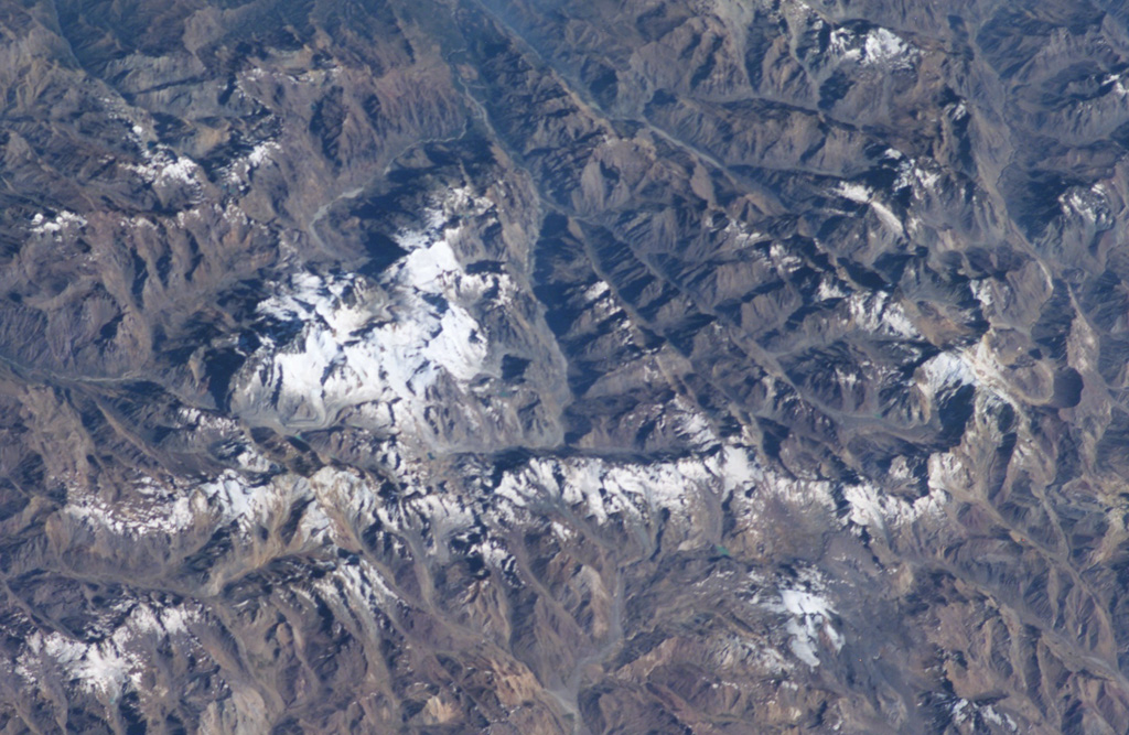 A complex of snow-covered cones (left-center) partially fills the 30 x 45 km wide Caldera del Atuel, which lies just east of the Argentina-Chile border.  The headwaters of the Río del Atuel drain to the SE through a wide breach in the caldera rim (top center) in this NASA International Space Station image (with north to the bottom left).  The snow-covered Volcán Overo and Sosneado complexes in the eastern part of the caldera contain numerous very youthful basaltic-to-andesitic pyroclastic cones and lava flows.   NASA International Space Station image ISS010-E-19060, 2005 (http://eol.jsc.nasa.gov/).