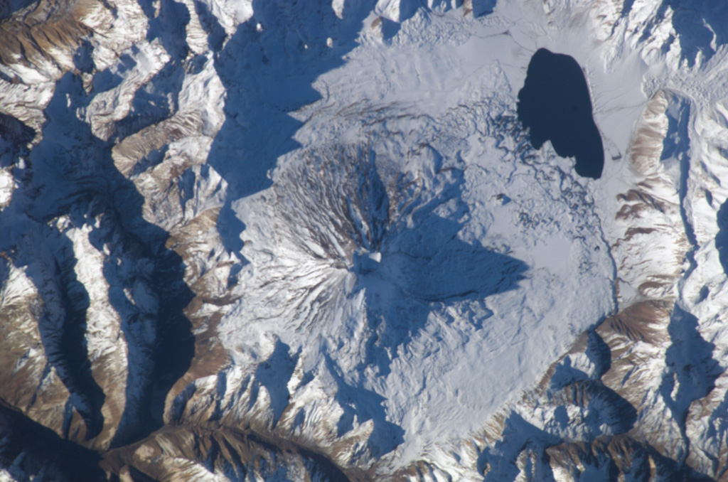 Conical Maipo volcano rises above the floor of Diamante caldera in this NASA International Space Station view (with north to the top).  A series of flank vents on the eastern side of the volcano produced lava flows that give the western shoreline of Laguna Maipo and irregular outline; a lava flow in 1826 blocked drainages on the caldera floor, forming the lake.  The 15 x 20 km Diamante caldera was formed during a major explosion eruption about 450,000 years ago. NASA International Space Station image ISS009-E-7182, 2004 (http://eol.jsc.nasa.gov/).