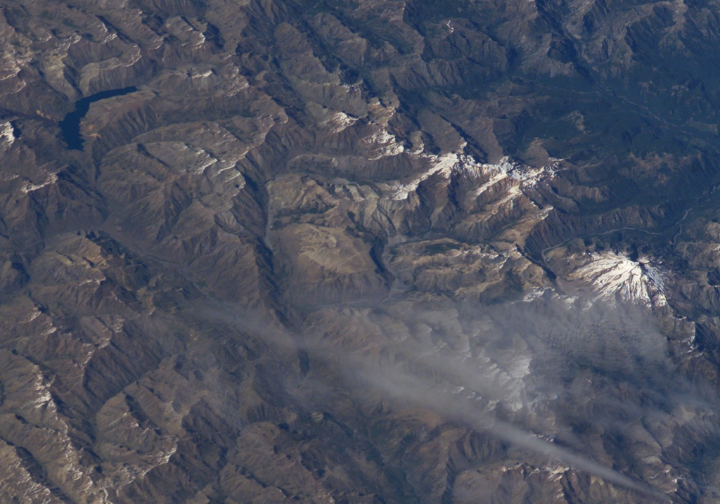 The small light-brown area at the center of this NASA International Space Station image (with north to the bottom right) is Volcán Lomas Blancas.  This small shield-like 2268-m-high stratovolcano of late-Pleistocene to Holocene age is located about 15 km SE of snow-capped Nevado de Longaví volcano (right-center).  A 2.3-km-wide caldera, possibly formed by edifice collapse, can been seen opening to the SE.  Pumice deposits probably originating from Nevado de Longaví blanket the volcano.  The crescent-shaped lake at the upper left is Laguna del Dial. NASA International Space Station image ISS008-E-7432, 2003 (http://eol.jsc.nasa.gov/).