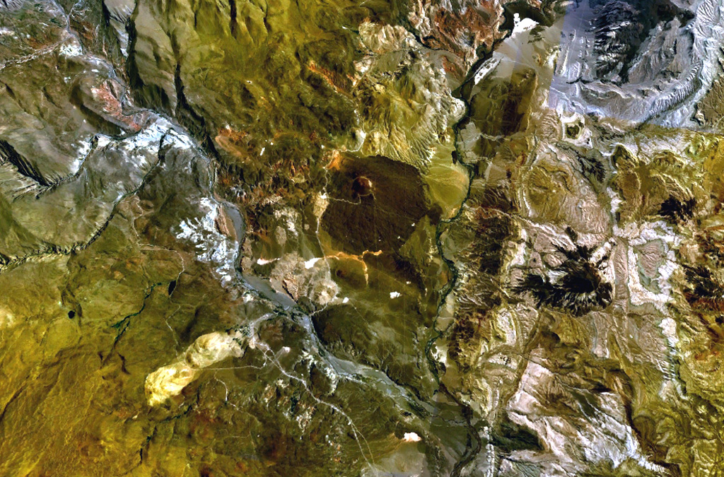 The small stratovolcano surrounded by an apron of lava flows in the center of this NASA Landsat image (with north to the top) is Cochiquito volcano.  The alkaline basaltic volcano has eight satellitic cones and lies near the junction of the Río Barrancas (cutting diagonally across the image from the upper left) and the Río Grande (right-center).  Lava flows from the Sillanegra pyroclastic cone complex can be seen across the Río Grande below and to the right of Cochiquito. NASA Landsat 7 image (worldwind.arc.nasa.gov)