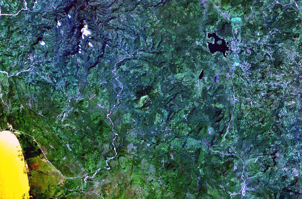 The small circular volcano at the center of this NASA Landsat image east (right) of the Río Pacora (left of center) is Cerro el Ciguatepe.  This volcano lies in the Nicaraguan interior highlands, east of yellow-colored Lake Managua (lower left).  A prominent breach can be seen in the SW wall of the well-preserved 1.5-km-wide crater.  A small lava flow extends a short distance beyond the base of the cone through the breach, and a blocky plug dome was emplaced in the center of the crater.  The dark-colored lake at the upper right is Laguna Moyua.  NASA Landsat 7 image (worldwind.arc.nasa.gov)