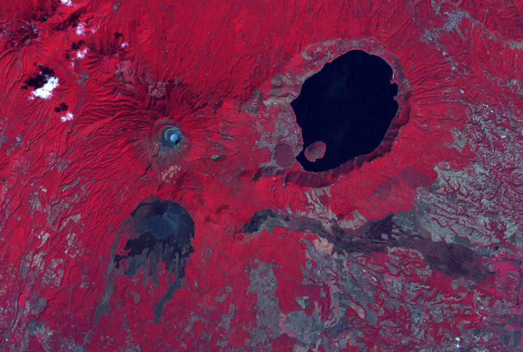 The summit crater complex of Santa Ana volcano with its small light-bluish crater lake is visible at the left-center in this false-color ASTER satellite image (N is to the top; this image is approximately 30 km across). The lake-filled Coatepeque caldera is east of Santa Ana, and Izalco volcano with its lava flows are to the south. A fissure was the source of an eruption in 1722 CE from a scoria cone (center) on the SE flank that produced the lava flow across the image to the lower right. NASA ASTER image, 2001 (https://earthobservatory.nasa.gov/).