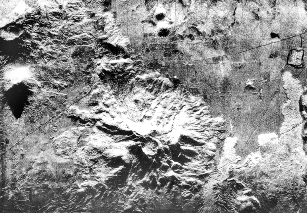The deeply eroded Rota stratovolcano with its circular 1-km-wide summit crater lies at the bottom-center of this radar image.  The latest eruption from the 832-m-high volcano produced thick andesitic lava flows NW of the summit, which extend nearly to the Malpaisillo road cutting diagonally across the image to the upper right.  Two small NNW-SSE-trending lava domes (top-center), El Bosque, are located on the plain 2 km north of the flank of Rota (top-center).  The Telica volcanic complex is visible at the upper left and lava flows from Las Pilas at the far right.   Radar image, 1971 (courtesy of Jaime Incer).
