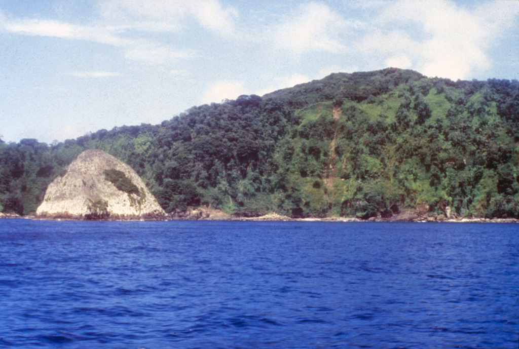 The light-colored pyramidal island at the left is a small island of trachytic rocks between Bahia Wafer and Bahia Chathan, on the NE side of Cocos Island.  The plug-like islet lies north of a massive lava dome lying between the two bays and consisting of flow-banded benmoreitic, trachytic, and quartz trachytic rocks. Photo by Pat Castillo, 1984 (Scripps Institution of Oceanography, University of California San Diego).