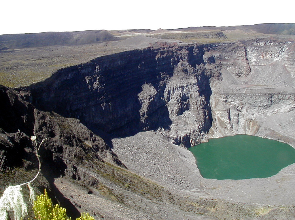 The greenish ~300-m-diameter Chahalé crater lake in the summit caldera complex of Karthala volcano is seen here in August 2003 before an eruption in April 2005. The photo, taken by an automatic camera located at the summit, looks from the NNE towards the SSW. Karthala is the southernmost and largest of the two shield volcanoes forming Grand Comore Island (also known as Ngazidja Island) and contains a 3 x 4 km summit caldera generated by repeated collapse. It has elongated rift zones extending to the NNW and SE. Photo by Nicolas Villenueve, 2003 (Université de la Réunion).