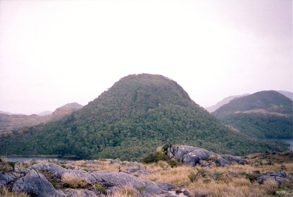 A young lava dome on Isla Cook is viewed from the east.  This group of andesitic lava domes and pyroclastic cones, known as Volcán Feuguino or Volcán Cook, mark the southernmost Holocene volcanoes of the Andes.  They occupy a broad peninsula forming the SE end of Isla Cook and are unaffected by glacial erosion that scoured the underlying plutonic rocks.  Passing navigators observed possible eruptive activity in the direction of Cook in 1712 and the eruption of incandescent ejecta in 1820.  Photo by Scott Dreher, 2005 (University of Durham).