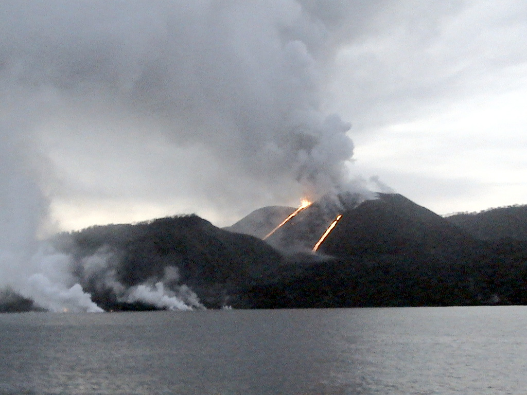 A view from off the west coast of Barren Island on 26 August 2005 shows a Strombolian eruption from the central scoria cone. The main crater was active and both explosive and effusive activity had shifted to the N. Two incandescent lava flows are visible along the slopes of the scoria cone, and steam-and-gas plumes mark the entry point of the lava flows into the sea. Photo by A. Kar, 2005 (Central Ground Water Board).