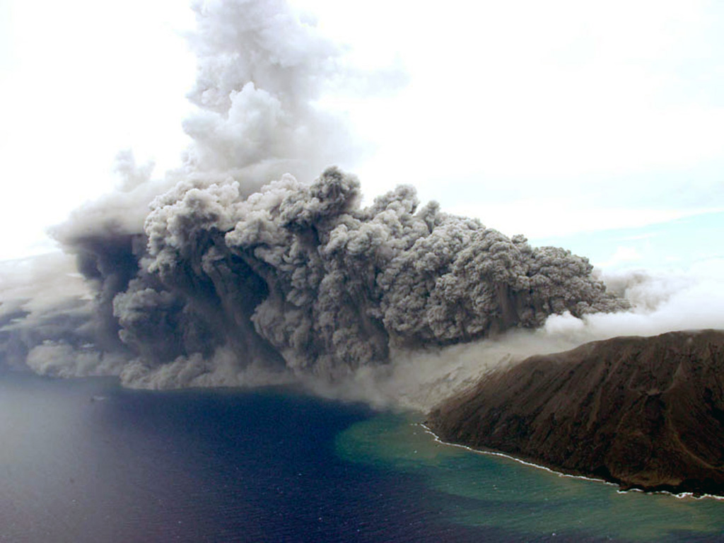 An ash plume rises from a vent at the E crater (far right) of Anatahan as seen from a helicopter looking NW on 24 August 2005. Eruptive activity had begun in 2004, when a new lava dome was seen on 12 April, along with fresh ejecta within the crater. Intermittent explosive activity occurred throughout the year. In 2005 the crater floor was almost entirely covered by fresh lava out to a diameter of ~1 km. Explosive eruptions in April, June, and July 2005 produced ash plumes to as high as 15 km. Photo by Takeshi Matsushima, 2005 (Kyushu University).