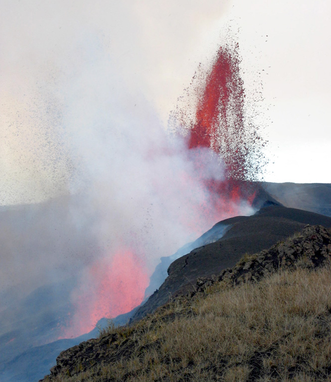 A 150-m-high lava fountain rises on October 23, 2005 from one of four active vents that define the active fracture system at the base of the northern inner wall of Sierra Negra's caldera.  An eruption began on October 22, 2005 from a 2-km-long, roughly E-W-trending fissure vent along the north caldera rim, initially producing a 15-km-high eruption column.  Some lava flows traveled down the north flank, but the bulk of the lava flows traveled into the caldera and followed its east wall before being deflected by the southern caldera wall to the west. Photo by Minard Hall, 2005 (Escuela Politecnica Nacional, Quito).