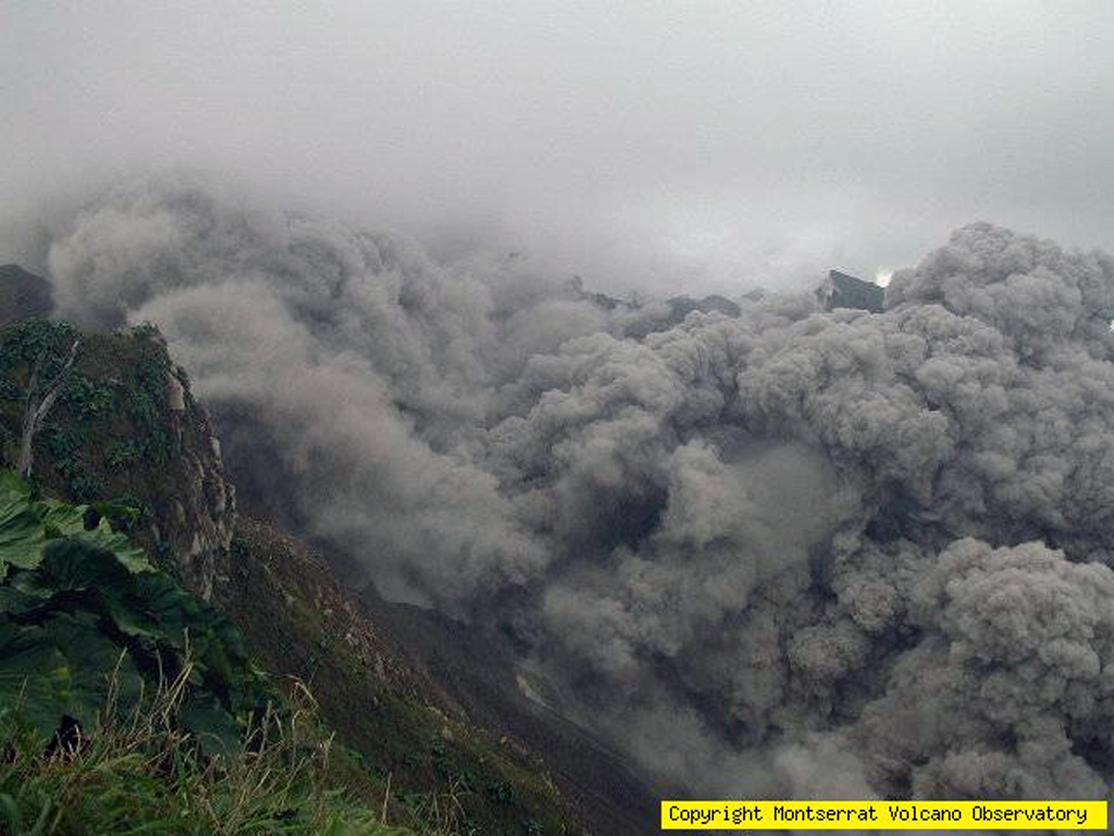 A pyroclastic flow descends the upper part of the Tar River valley on Soufrière Hills volcano as seen from the NE on November 22, 2005.  During renewed activity beginning in April 2005, pyroclastic flows were first observed on June 28.  Following period of rapid lava dome growth beginning on November 4, pyroclastic flows became more common.  On November 4 a pyroclastic flow down the Tar River valley reached to within a kilometer of the sea. Photo courtesy of Montserrat Volcano Observatory, 2005.