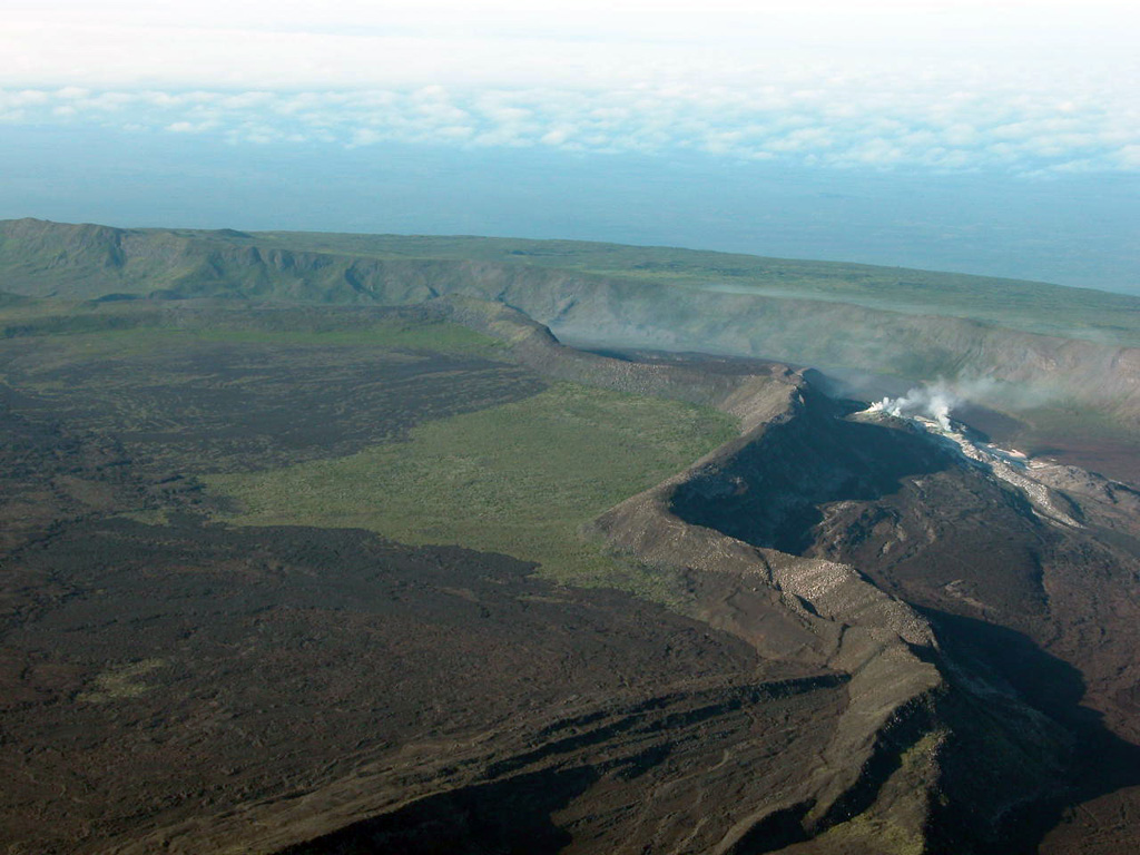 An aerial view of the SW caldera floor of Sierra Negra volcano shows El Azufre fumarolic field and the trap-door fault to the left.  This sinuous 14-km-long, N-S-trending ridge occupies the west part of the caldera floor, which lies only about 100 m below its rim.  El Azufre, the largest fumarolic area in the Galápagos Islands, lies within a graben between this ridge and the west caldera wall.  The broad shield volcano of Sierra Negra at the southern end of Isabela Island contains a shallow 7 x 10.5 km caldera that is the largest in the Galápagos Islands.   Photo by Patricio Ramon, 2005 (Instituto Geofisca, Escuela Politecnica Nacional).