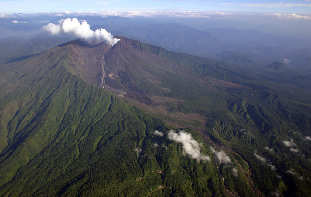 A steam-and-gas plume rises from the central cone of Reventador volcano in this March 11, 2005 aerial view from the SE.  Several lava flows generated during eruptions in 2002 and 2004-2005 are visible on the south and SE flanks of the central cone.  The 3562-m-high central cone was constructed within the large 4-km-wide horseshoe-shaped caldera breached to the east (lower right).  The caldera was formed during a major collapse of the volcano, which produced a massive debris avalanche that swept into the Amazon basin. Photo by Patricio Ramon, 2005 (Instituto Geofisca, Escuela Politecnica Nacional).