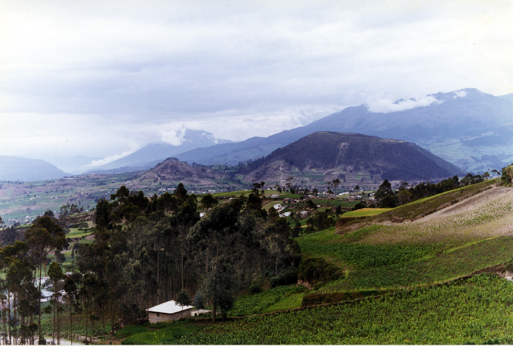 Cerro Tulabug (right-center), part of the Licto group of basaltic-andesite to andesitic scoria cones, is seen here from the SW.  The cones lie along the Río Chambo about 25 km SE of the city of Riobamba and just north of the town of Licto and form the southernmost area of Quaternary volcanism in the Interandean valley of Ecuador.  The cloud-draped conical volcano in the left-center background is Reventador, and the Cordillera Real forms the right horizon. Photo by Patricio Ramon, 1998 (Instituto Geofisca, Escuela Politecnica Nacional).