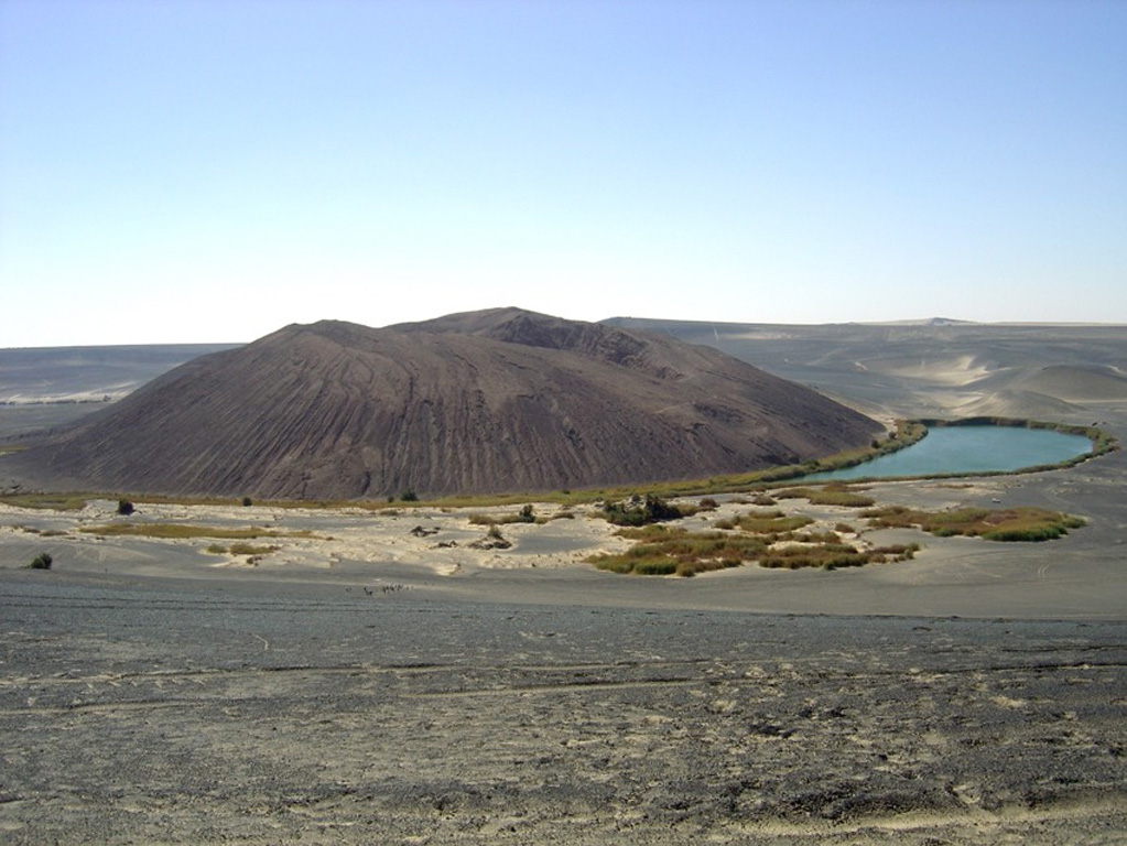 The central cone of the isolated Wau-en-Namus volcanic field lies within a 4-km-wide caldera in the Sahara desert of south-central Libya.  Three small salt lakes, one of which is seen at the right margin of the cone in this view from the south, contribute to its name, which means "Oasis of Mosquitoes."  The youthful appearance of the central cone has suggested it may be as young as a few thousand years, although the arid climate may mask its actual age.   Photo by Jacques-Marie Bardintzeff, 2006 (Université Paris-Sud).
