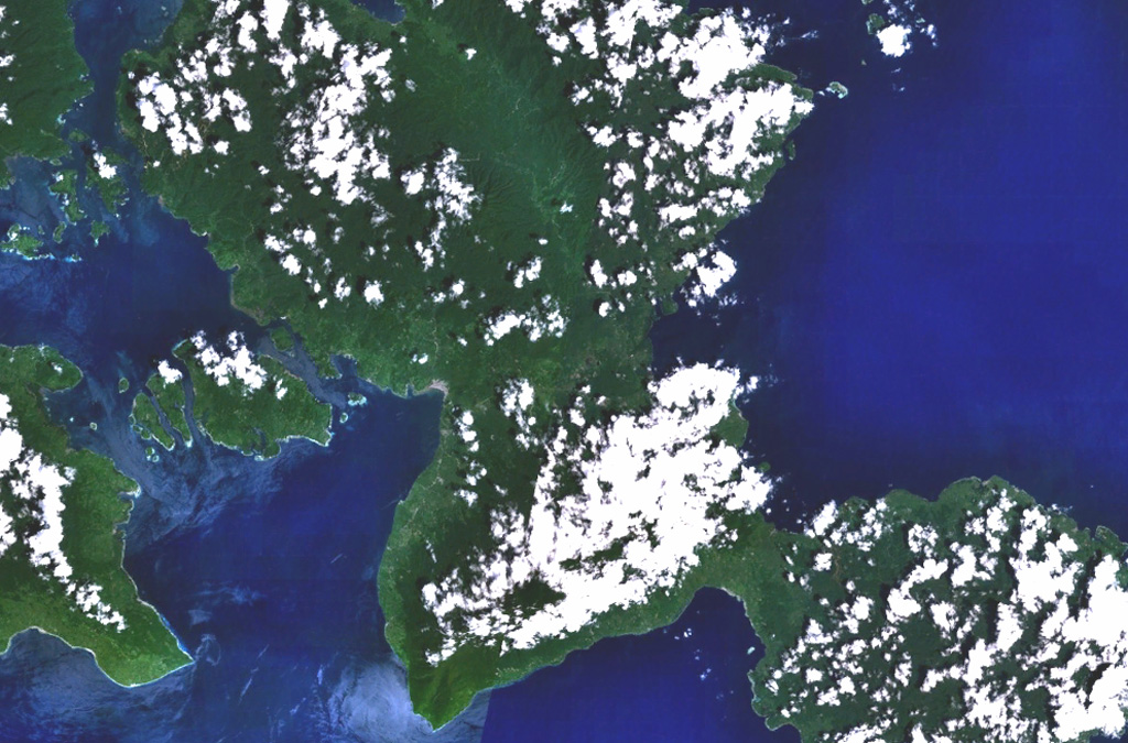 Bukit Amasing (Amasing Hill) is the largest and NW-most of a group of three small andesitic volcanoes located just above the center of this NASA Landsat image (with north to the top).  These volcanoes lie along a NW-SE line in central Bacan Island.  Two smaller volcanoes, Cakasuanggi and Dua Saudara, were constructed to the SE, north of the metamorphic complex of the Sibela Mountains, the cloud-covered massif at the bottom center.  Other young volcanoes of the Bibinoi group lie at the SE peninsula of Bacan Island (lower right). NASA Landsat 7 image (worldwind.arc.nasa.gov)