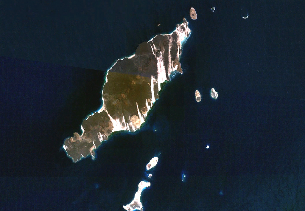 The 20-km-long island of Hanish is seen in this composite NASA Landsat image (with north to the top). Alignment of vents along a prominent NE-SW trend gives the island its elongated shape. Short lava flows reached the coast on both sides of the island, including a very youthful flow prominent on the NW coast. Initial phreatic eruptions were followed by the formation of basaltic tuff and spatter cones that produced fluid lava flows. Suyul Hanish Island lies at the bottom center, and other offshore island lie along the regional NE-SW trend. NASA Landsat 7 image (worldwind.arc.nasa.gov)