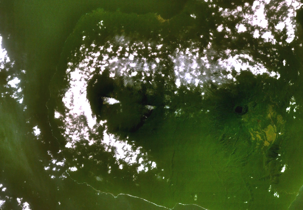 A broad caldera, partially surrounded by clouds left of center, cuts the summit of San Carlos volcano. This a basaltic shield volcano forms the toe on the SW side of boot-shaped Bioko (Fernando Poo) Island. This NASA Landsat view (with north to the top) also shows neighboring San Joaquin volcano, with its smaller lake-filled caldera, at the right. NASA Landsat 7 image (worldwind.arc.nasa.gov)