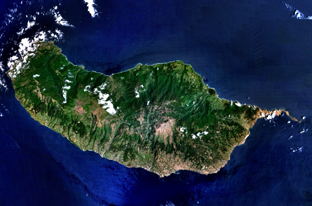 The 90-km-long island of Madeira is seen in this NASA Landsat image (with north to the top).  Construction of the volcano along E-W-trending rift zones was followed by a period of extensive erosion and possible edifice collapse.  The capital city of Funchal lies along the SE coast, east of a large caldera that extends to the southern coast. Late-stage eruptions were scattered throughout the island, although the youngest activity took place along the west-central crest of the island, on the Paul da Serra plateau near the cloud near the center of this image.  NASA Landsat 7 image (worldwind.arc.nasa.gov)