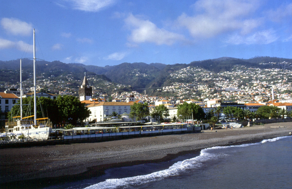 Funchal, the capital city of Madeira, is seen here along the southeast flanks of the massive shield volcano forming the island. The island is the emergent summit of a volcano that rises about 6 km from the seafloor in an E-W-trending rift zone. Following a period of extensive erosion, renewed eruptions produced cinder cones and lava flows that traveled down dissected valleys. Photo by Paul Bernhardt.