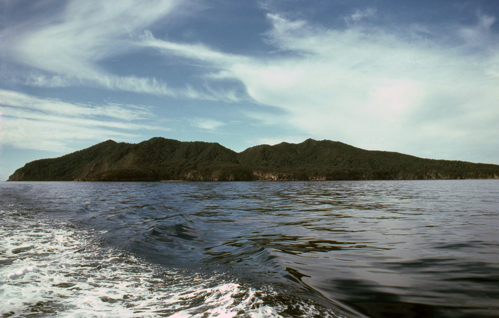 Mayor Island in the Bay of Plenty is seen here from the W. The low, 4-km-wide island, also known as Tuhua, is the summit of the broad 15-km-wide volcano. A 3-km-wide caldera formed during two or three collapse events, the latest of which followed a major explosive eruption about 6,300 years ago. Mayor Island was recognized as an active volcano only within the past two decades. Its latest eruption may have occurred only 500-1,000 years ago. Photo by Malcolm Buck, 1980.