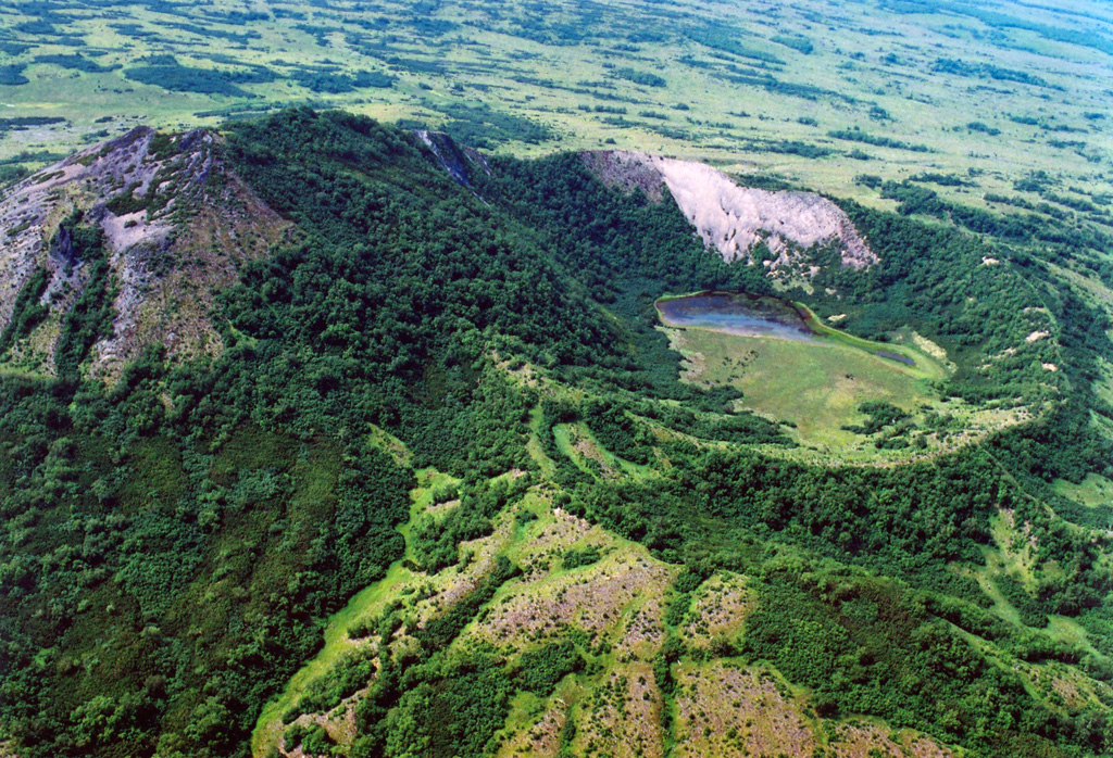 Kekuk crater on the lower northern flank of the Bolshoi-Kekuknaysky volcanic complex formed about 7,200 years ago. The 1-km-wide crater formed beside a lava dome (left) which likely was erupted immediately prior to formation of the crater. Bolshoi and Kekuknaysky are two large partially overlapping Pleistocene edifices that contain scoria cones on their flanks. Copyrighted photo by Adam Kirilenko, 2003.